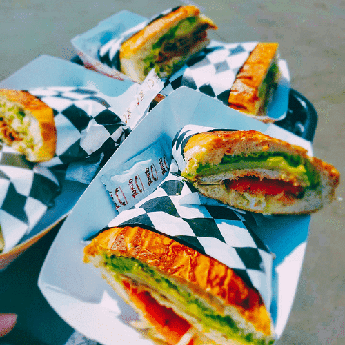 Plates of sandwiches with various fillings on checkered paper.