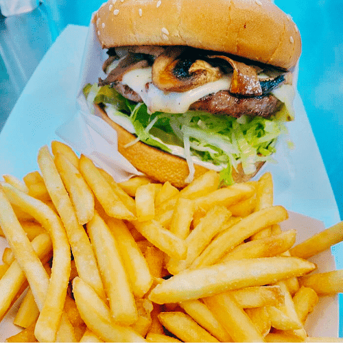 Juicy burger with melted cheese and fries on a plate.