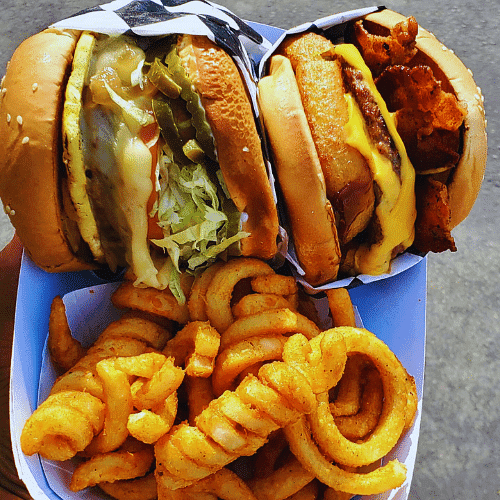 A double cheeseburger with curly fries and onion rings.