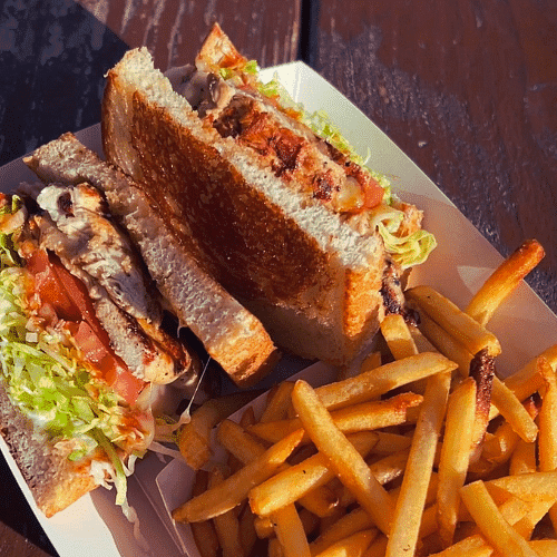 A sandwich with fries on a sunny table.