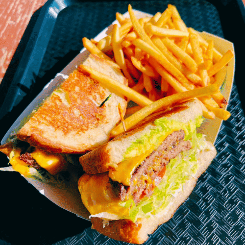 Cheeseburger with fries served in a black tray.